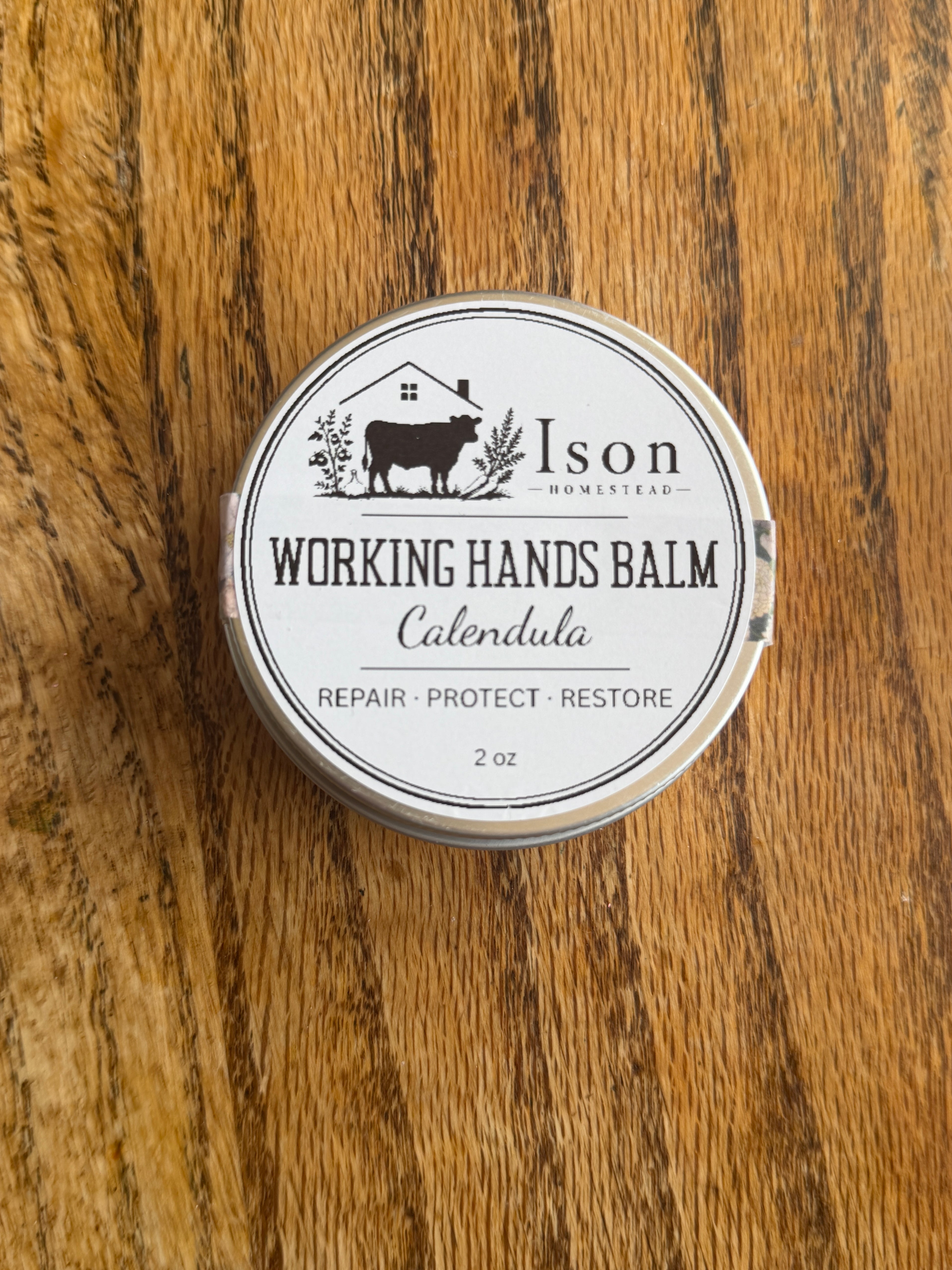 Ison Working Hands Balm container on a wooden surface
