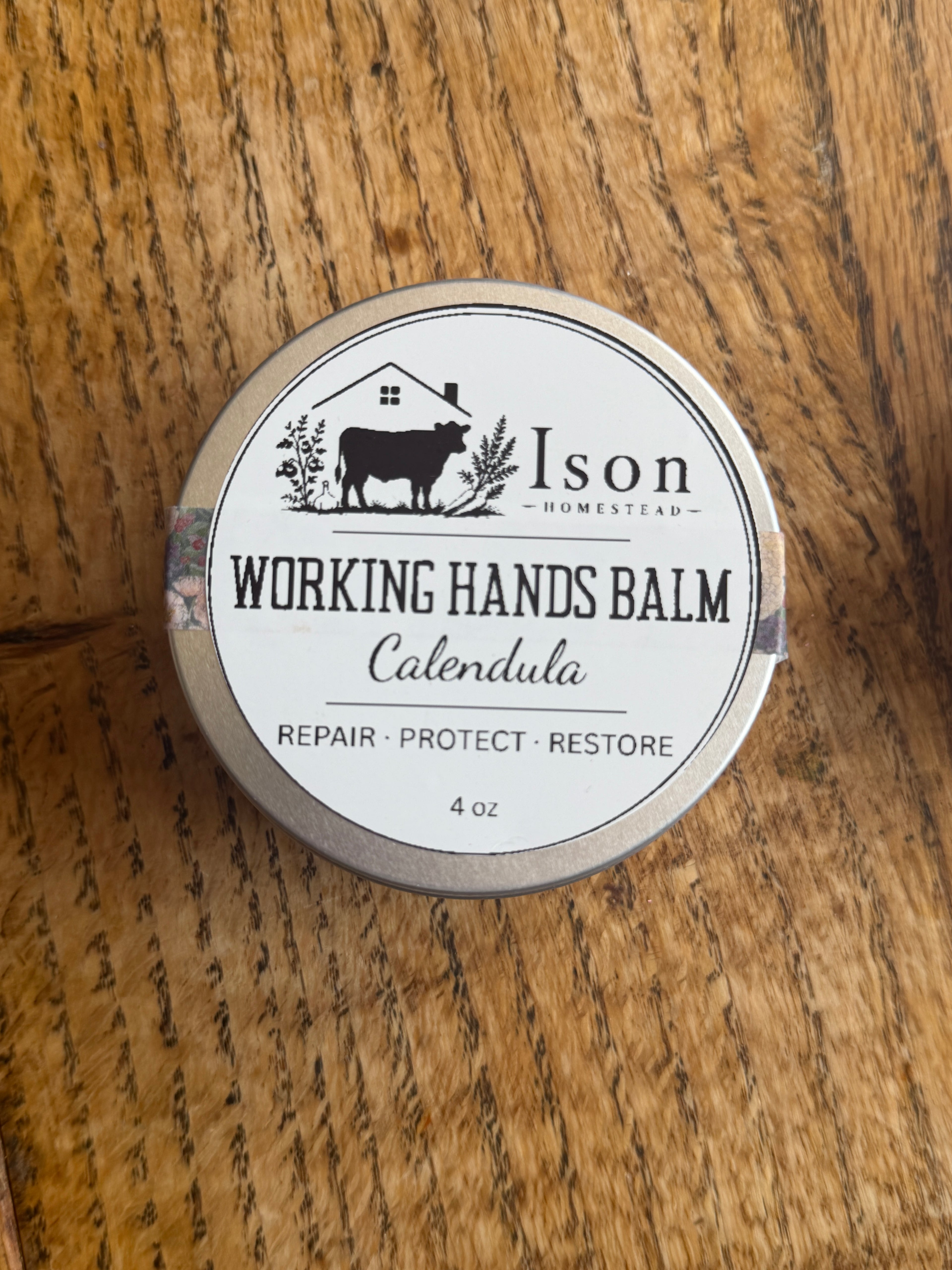 Tin of Ison Working Hands Balm on a wooden surface