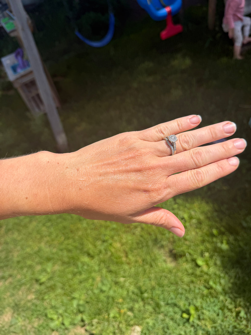 Hand with a ring on a grassy background with dandelion balm applied 